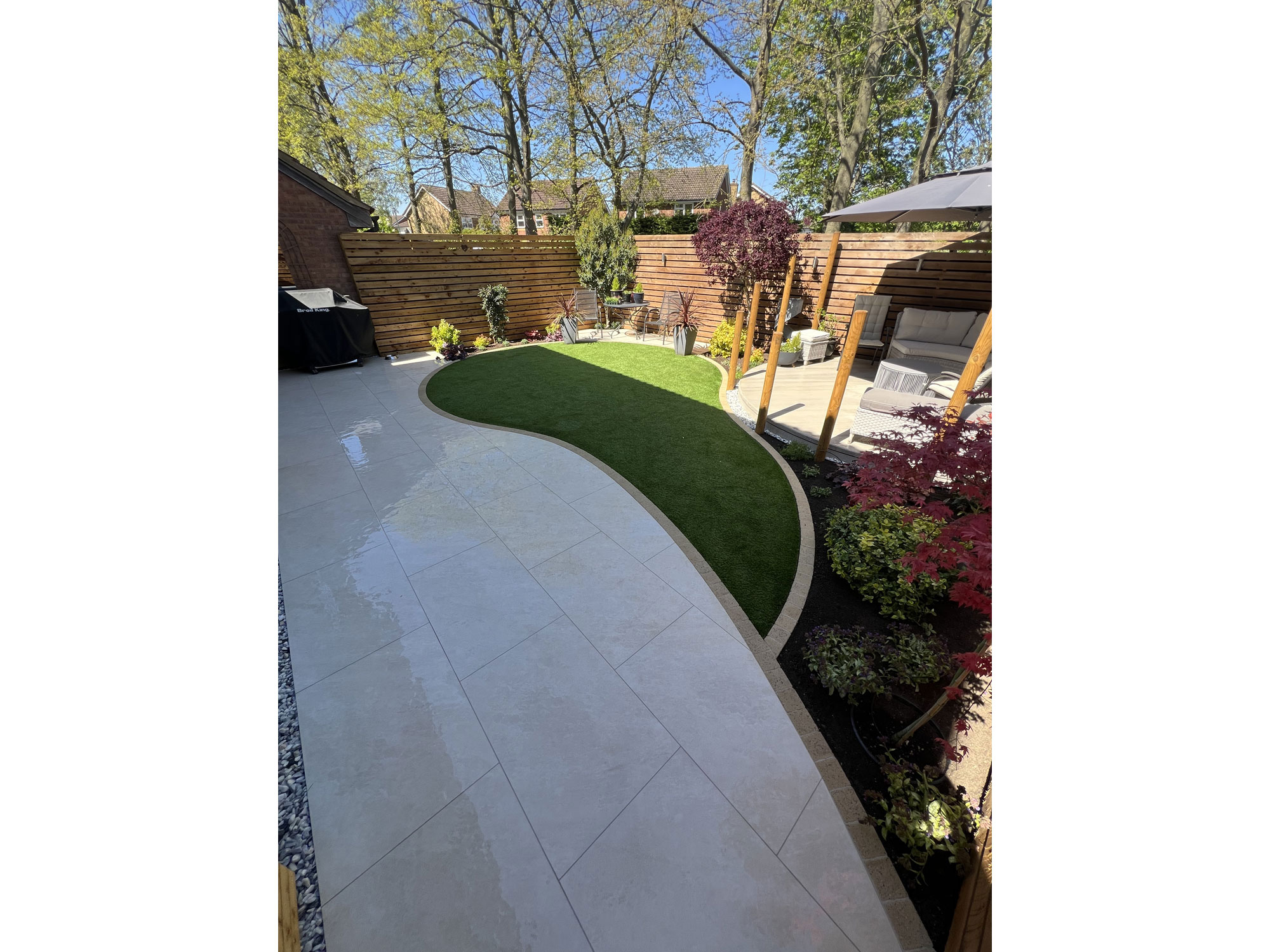 Curved composite decking with circular garden design and porcelain paving