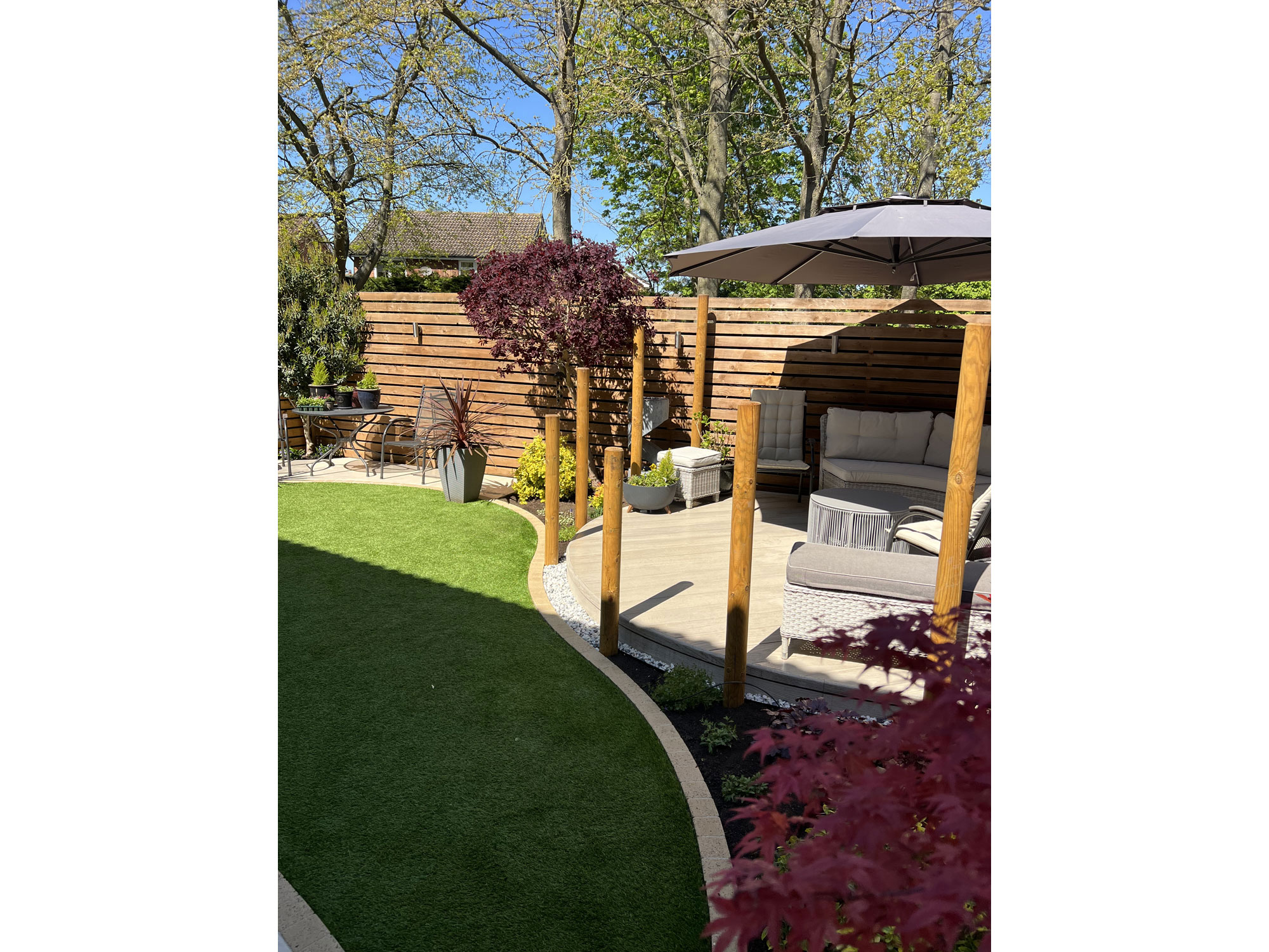 Bespoke circular decking area forming part of a curved garden landscaping design