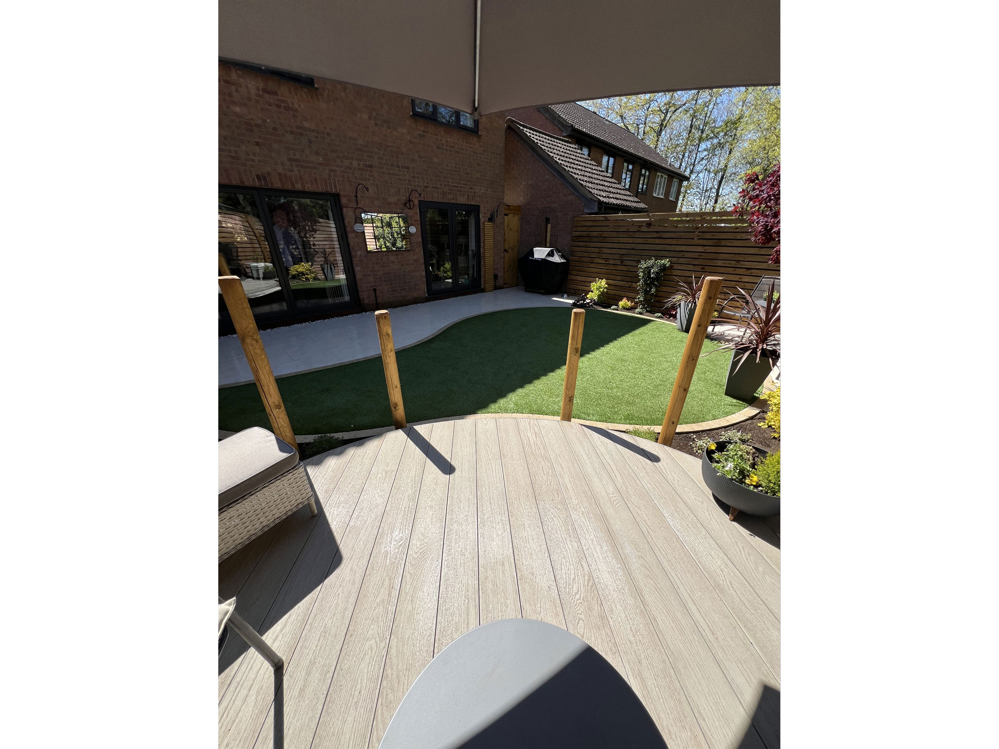 Curved garden design combining circular composite decking with porcelain paving