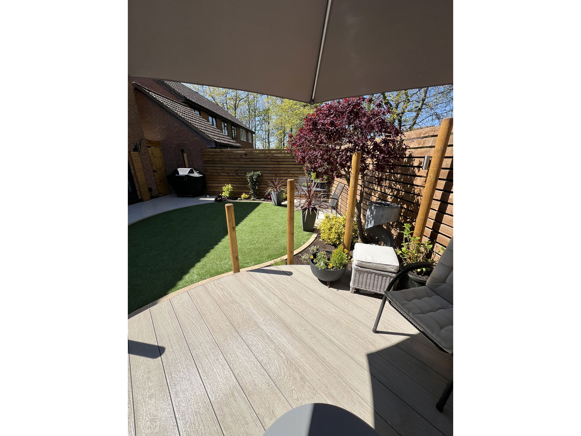 Durable composite decking with curved edges alongside a contemporary porcelain patio