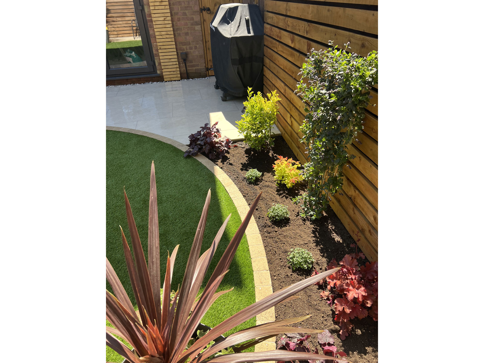Garden transformation featuring curved porcelain paving, composite decking and oak features