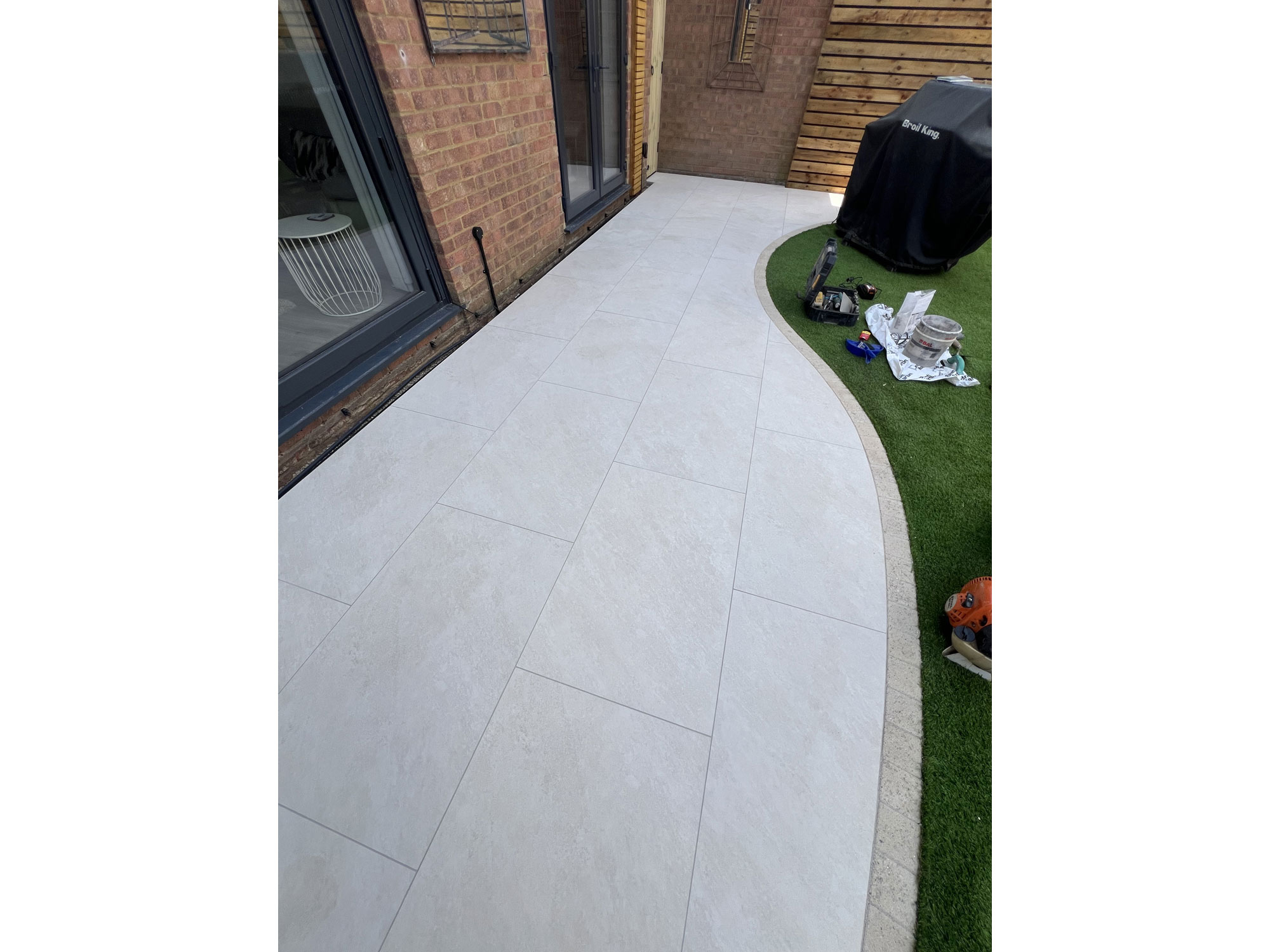 Curved garden landscaping with circular composite decking and contemporary porcelain paving