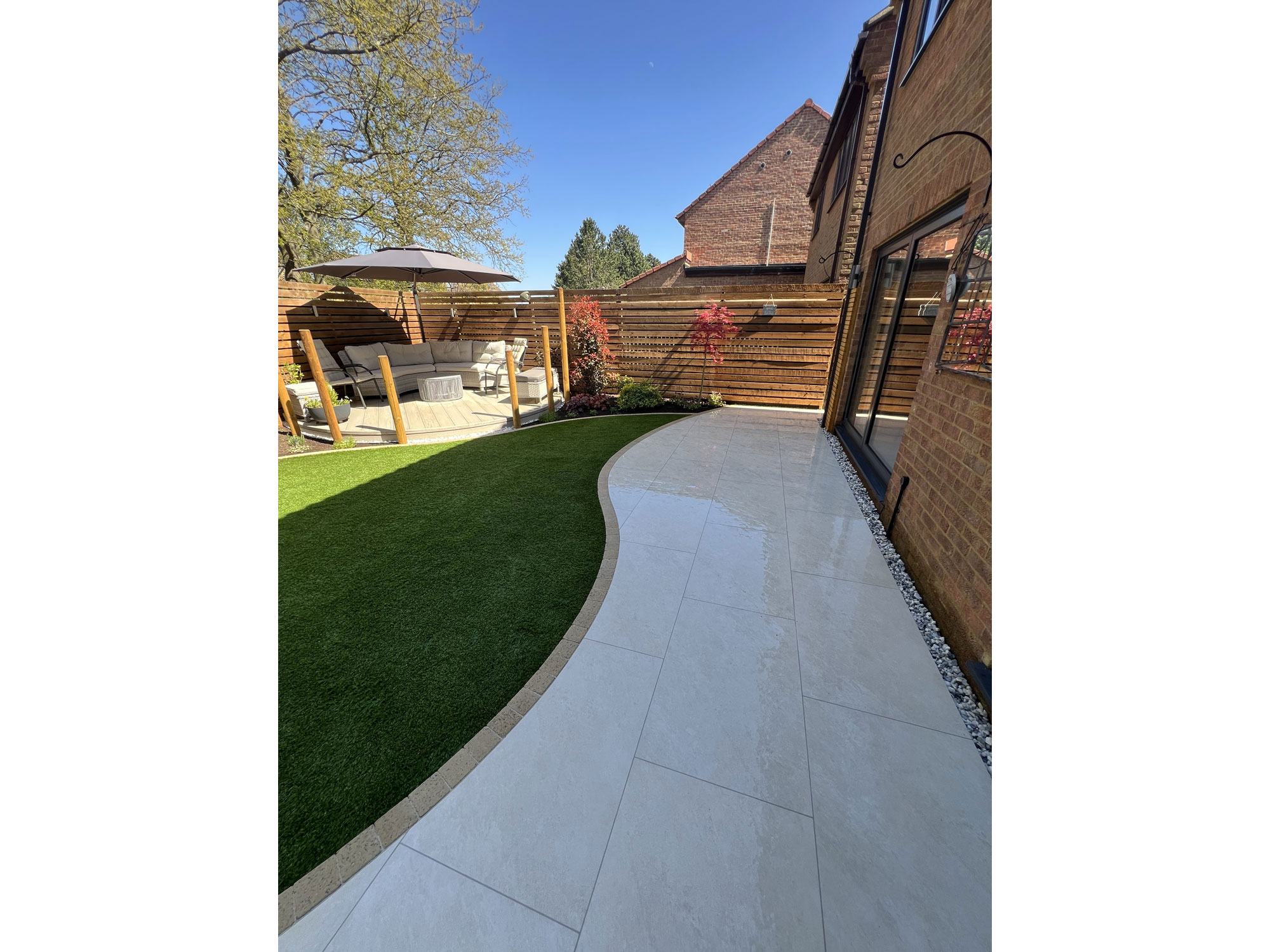 Contemporary circular composite decking and curved paving in a garden transformation