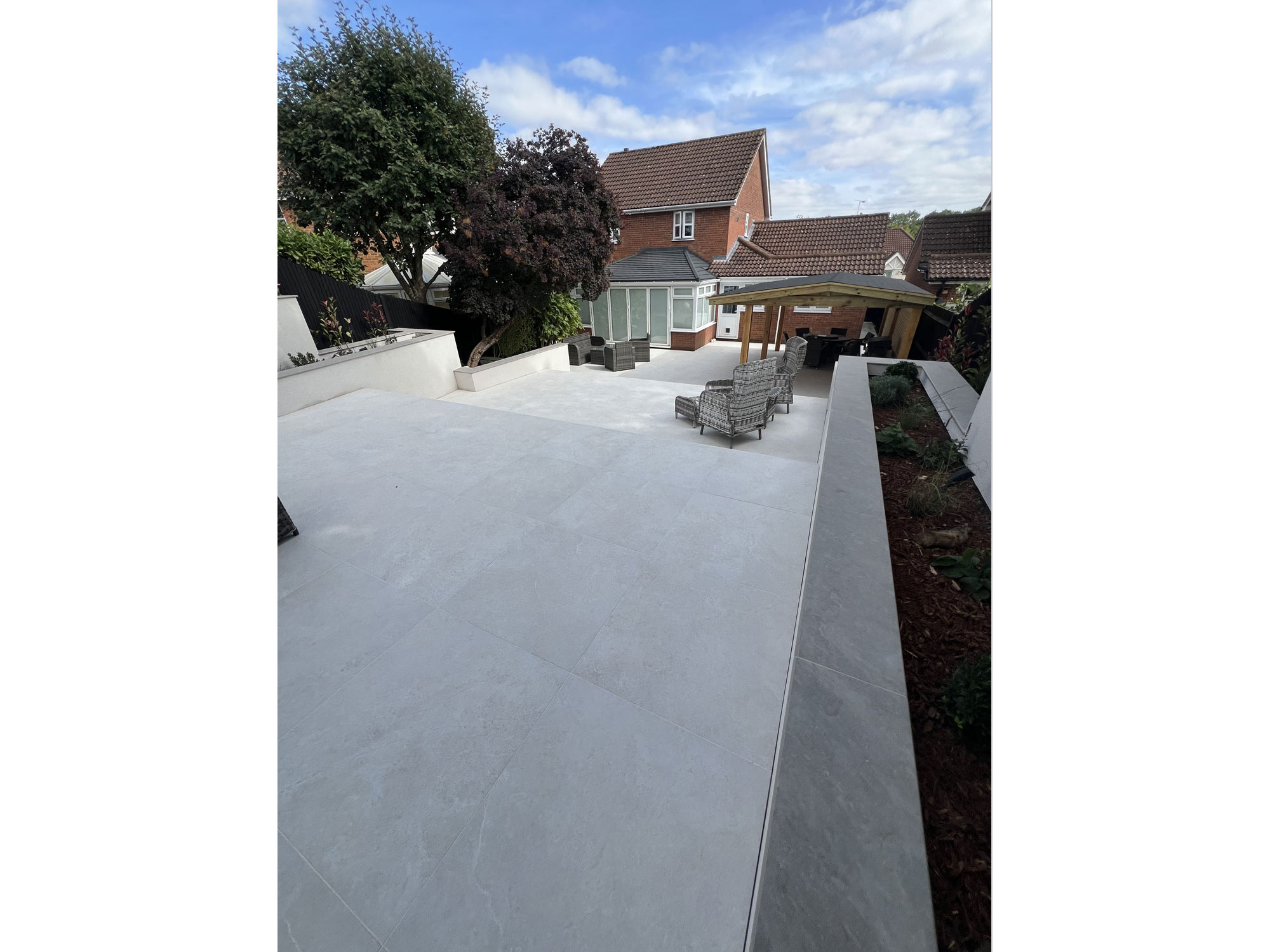Modern landscaped garden featuring porcelain paving and rendered feature walls