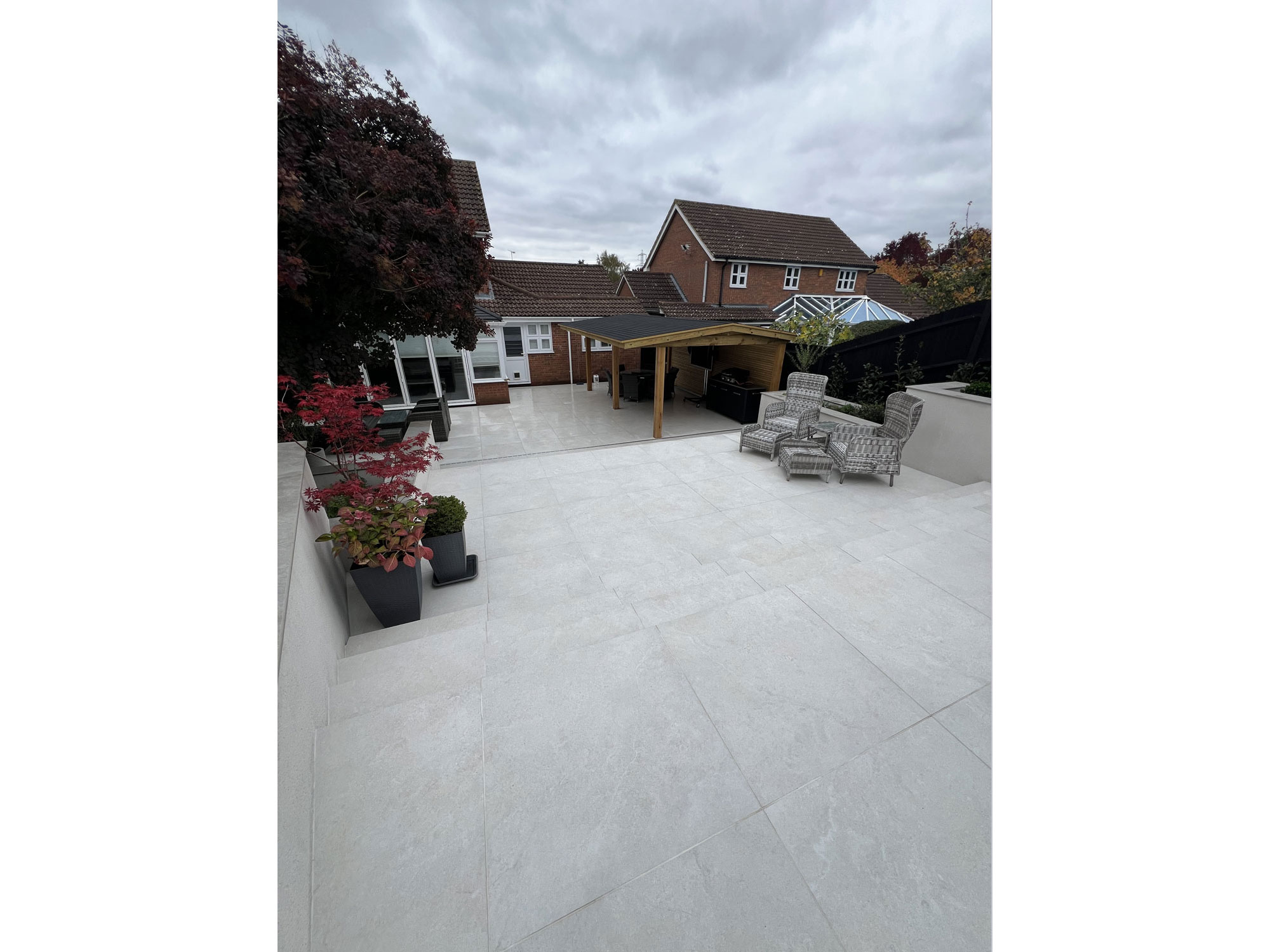 Contemporary outdoor BBQ area with porcelain patio tiles and landscaped garden